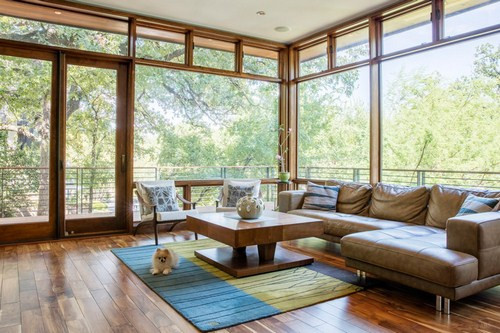 Sàn nhà cũng được thay đổi để trở thành sàn gỗ, đem lại một cảm giác ấm cúng cho toàn bộ không gian. Chiếc bàn cà phê tạo sự đồng điệu với chất liệu gỗ hình chữ L kết hợp cùng ghế da góp phần giúp cho không gian trở nên sang trọng và hiện đại hơn.