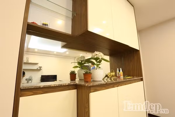 Phần giữa tủ được lắp gương phản chiếu giúp làm tăng vẻ mềm mại, vừa giúp nới rộng diện tích vừa dùng để đặt chậu cây và các vật trang trí nhỏ.