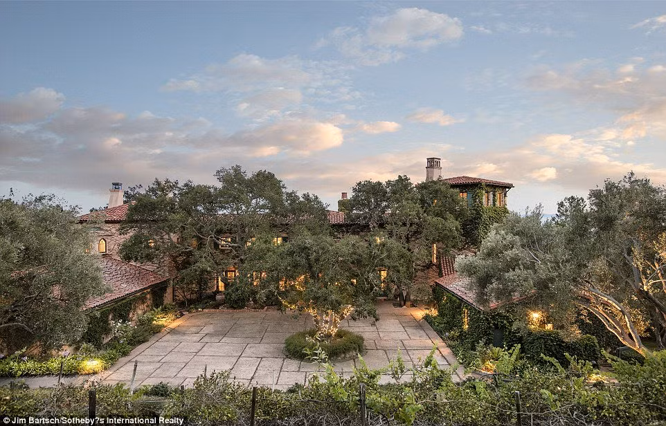 Các căn biệt thự xa hoa lợp ngói quây quanh một sân trời và được bao phủ với cây xanh.