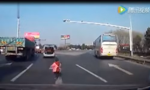 Cháu bé bị rơi từ phía sau xe ô tô đang cố gắng chạy theo chiếc xe của ông.(Ảnh từ clip)