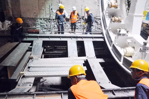 Tại công trường xây dựng nhà ga Ba Son có hơn 200 kỹ sư và công nhân xây các nhà ga hai tầng hầm ngầm. Trong ảnh các chuyên gia, công nhân đang lắp đặt các thanh ray của robot