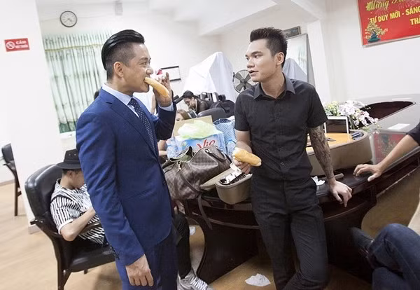 Tuấn Hưng và Khắc Việt vội vã ăn bánh mì lót dạ trước khi lên sân khấu biểu diễn.