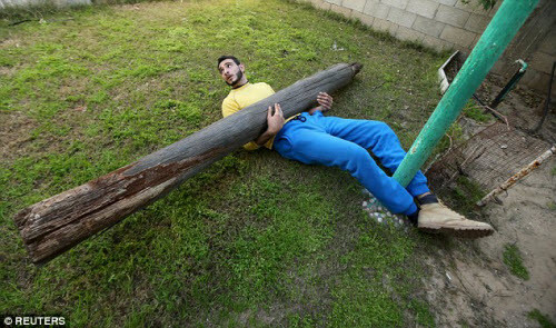 Chàng trai được mệnh danh là người khỏe nhất Dải Gaza nâng một khúc gỗ nặng trong khi nằm dưới đất.