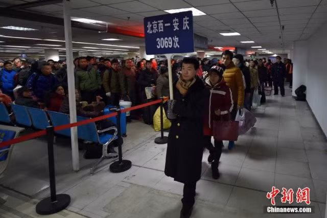 Nhân viên nhà ga cầm biển dẫn hành khách lên tàu để về quê đón Tết.