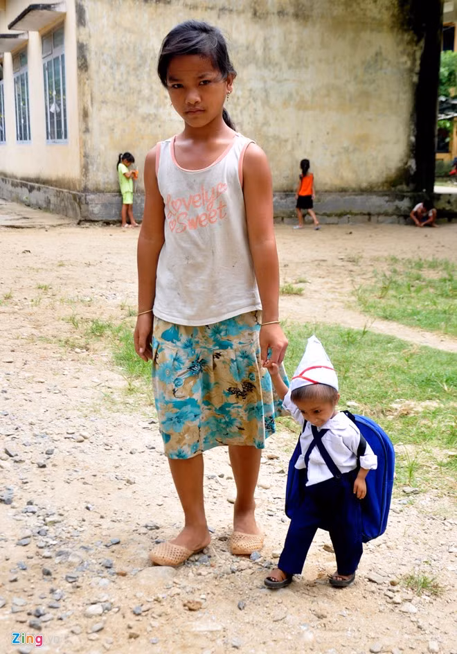 Giờ tan học, các anh, chị lớp lớn thay phiên nhau đưa K'rễ về khu nội trú giúp bé thay quần áo.