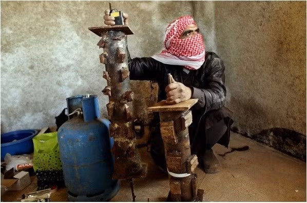 7. Bom ống tự tạo: Trong ảnh là một thành viên của quân nổi dậy cùng quả bom ống tự tạo do mình chế tạo.