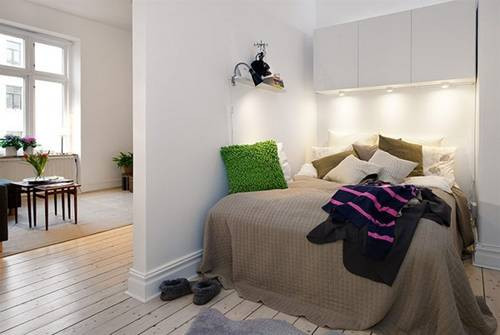 Để tiết kiệm không gian, giường ngủ được bố trí tại một góc nhà hơi xéo góc, bên trên giường có 3 tủ để lưu trữ đồ đạc gọn gàng. Một cánh cửa giữa khu vực phòng ngủ và phòng khách cũng đã được thiết lập nhằm đảm bảo tính riêng tư.