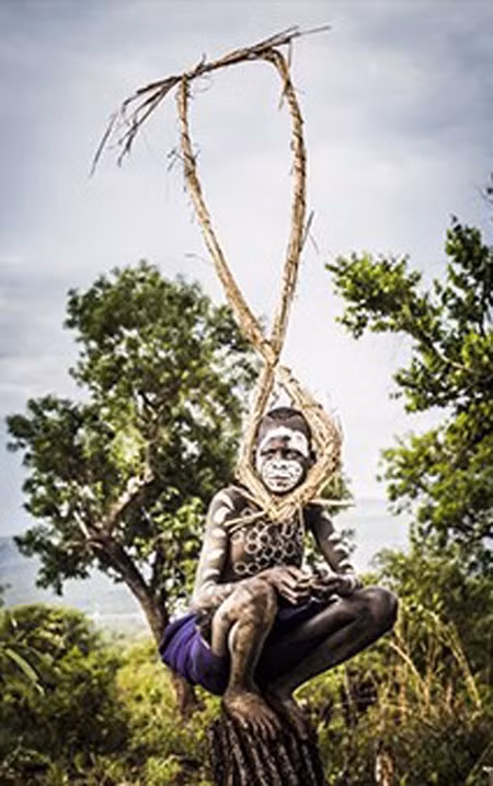 Seton phải mất ba ngày lái xe từ Addis Ababa để đến chụp ảnh bộ lạc Suri, cư trú tại làng Naregeer trong thung lũng Omo Rover - một khu vực xa xôi của Ethiopia, gần biên giới của Nam Sudan. Đây là bức ảnh đầu tiên trong ngày, bấm máy vào lúc 6h00, cậu bé bộ lạc Suri ngồi trên một thân cây khô giữa cánh đồng lúa miến.