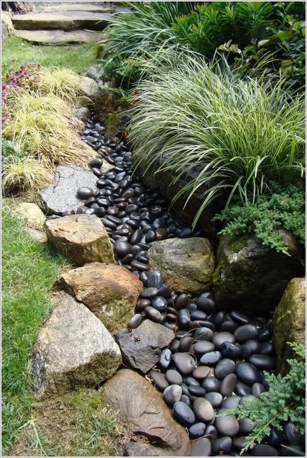 Thiết kế suối bằng đá cuội Với sân vườn mái dốc, bạn cũng cần chọn lựa và thực hiện những ý tưởng tạo nên những điểm nhấn độc đáo cho ngoại thất. Nếu khoảng sân vườn có diện tích nhỏ, bạn có thể thiết kế 'dòng chảy' bằng đá cuội, giúp góc nhỏ ngoài trời đẹp thú vị và ấn tượng hơn.