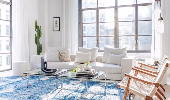 Phòng khách ngập tràn ánh sáng khi có tận hai khung cửa sổ rộng mở đón nắng bên ngoài vào. Không gian cũng được bố trí hết sức đơn giản với những nội thất mang kiểu dáng hiện đại. Ghế sofa dài kết hợp ghế tựa đơn có màu cùng tông với màu nền. Để tăng thêm nét đẹp tinh tế và hài hoà, pha chút ấn tượng trẻ trung, không gian được gia chủ đặt thêm cây cảnh và thảm với màu xanh nước biển.