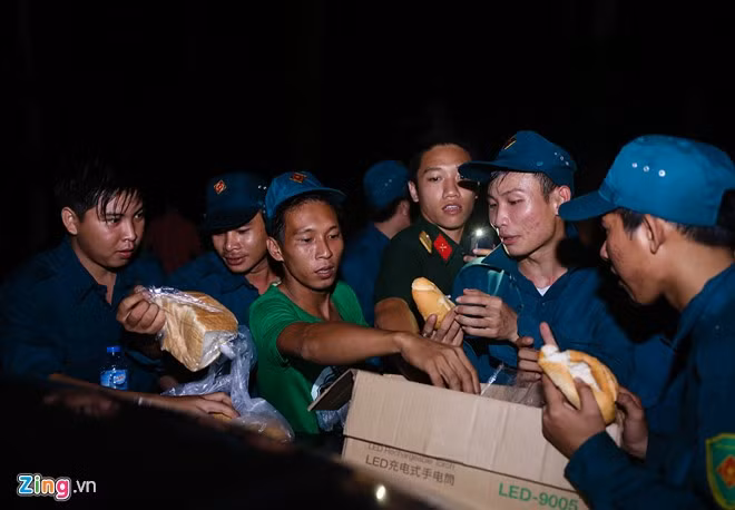19h ngày 18/10, lực lượng tìm kiếm đồng loạt rút xuống núi. Trong ảnh: Tốp cán bộ, chiến sĩ dân quân ăn bánh mì tại điểm dừng chân trên Thiền viện Viên Không (xã Tóc Tiên, huyện Tân Thành) sau một ngày tìm kiếm vất vả.