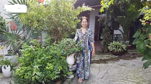 Mẹ Mai Ngô vui vẻ tạo dáng bên ngoài ngôi nhà.