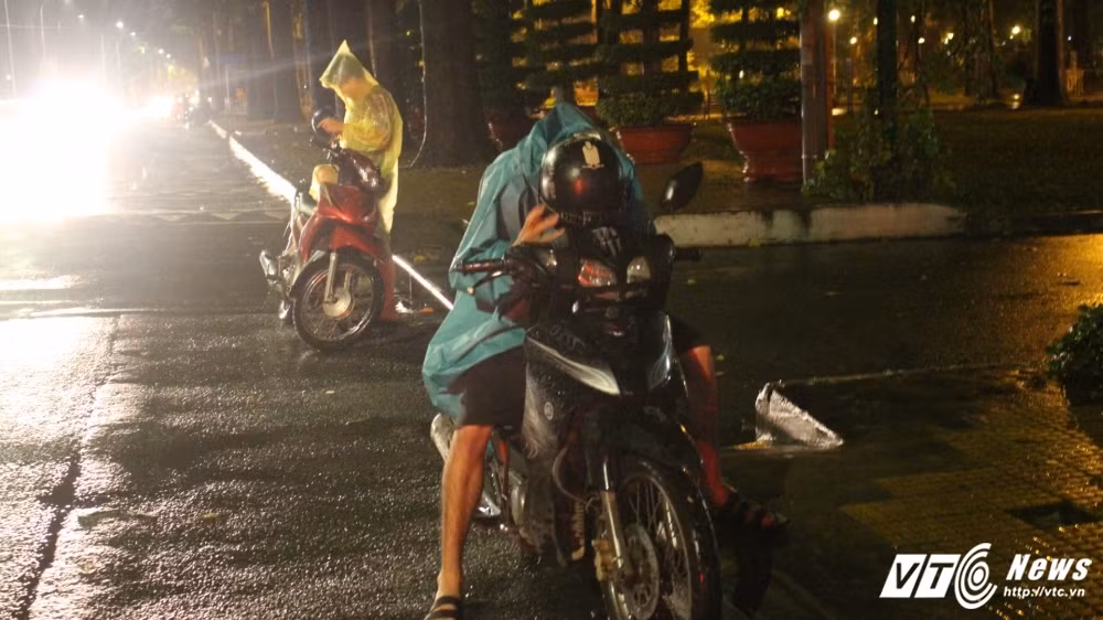 Một game thủ dán mắt sát màn hình điện thoại để vừa che mưa vừa nhìn được rõ Pokemon.