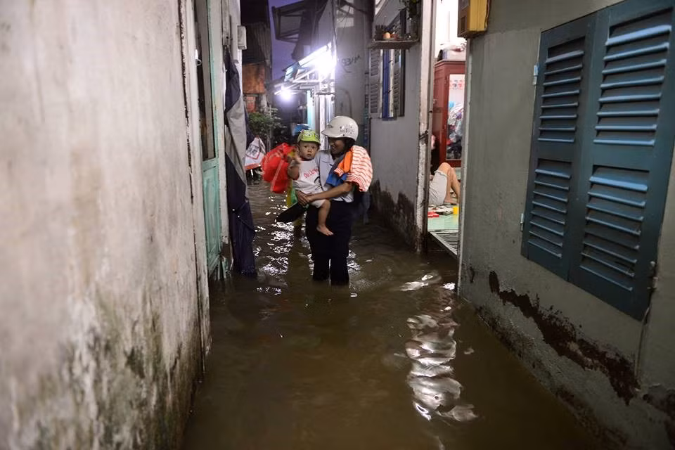 Triều cường cũng gây ngập nặng ở khu vực Thanh Đa (quận Bình Thạnh), Lương Định Của, Quốc Hương (quận 2). Đặc biệt khu vực này ngập sâu hơn dự kiến do kết hợp cơn mưa lớn vào chiều nay. Trong ảnh Chị Trinh (ngụ đường Xô Viết Nghệ Tĩnh, phường 25, quận Bình Thạnh) sợ cháu đêm không ngủ được do muỗi, ẩm lạnh nên mang theo đồ đạc tới nhà bà con gần đó. Ảnh: Lê Quân.