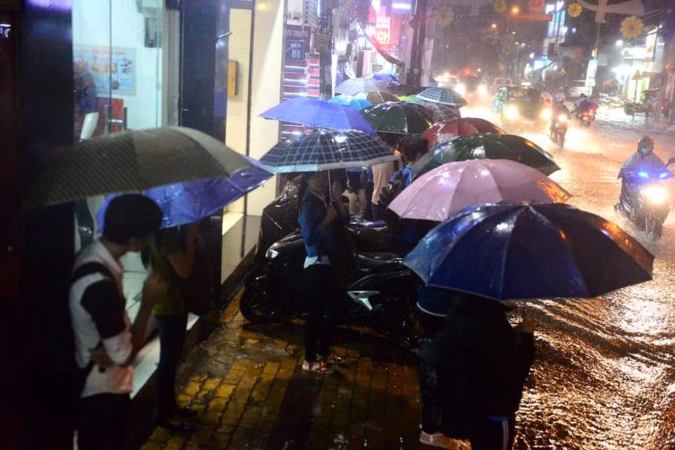 Sinh viên che dù đợi xe buýt trên đường Võ Văn Ngân, quận Thủ Đức. Ảnh: Tùng Tin.