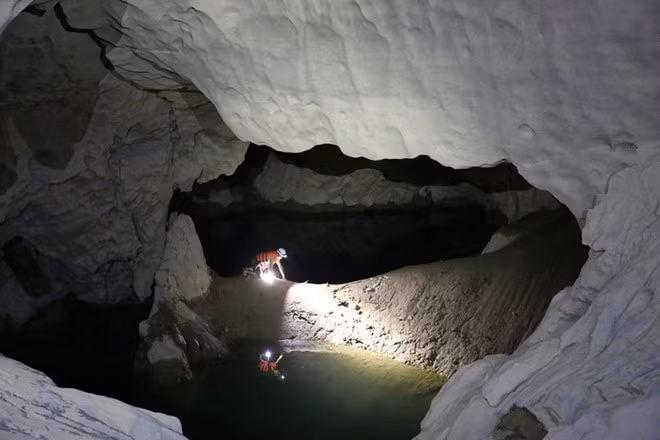 Tạ Nam Long cẩn thận di chuyển trên con đường bùn ướt trơn trượt.