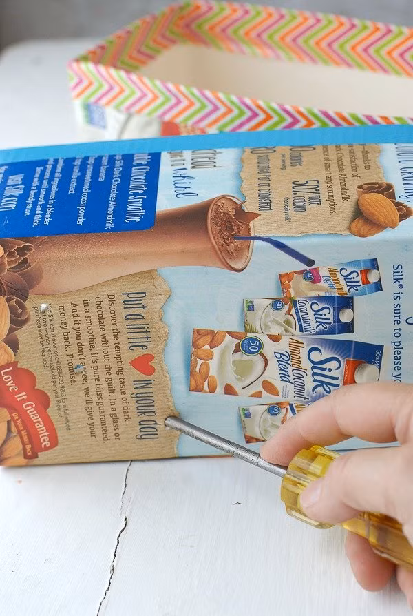 Bước 5: Dùng tuốc nơ vít chọc lỗ thoát nước ở dưới cùng của hộp. Cách làm này giúp cây trồng trong hộp sữa dễ thoát nước hơn.