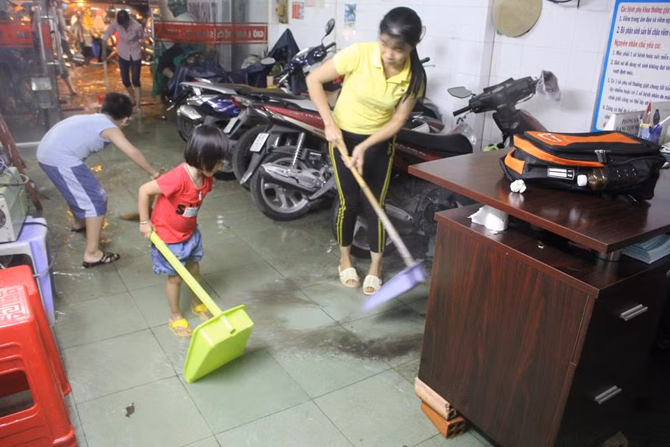 Người dân đẩy nước ra khỏi nhà trên đường (Quận Thủ Đức, TPHCM). Ảnh: Như Sỹ