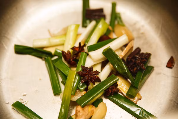 - Làm nóng dầu trong nồi, cho tỏi, hành, gừng, hoa hồi và quế vào đảo đều tới khi thơm.