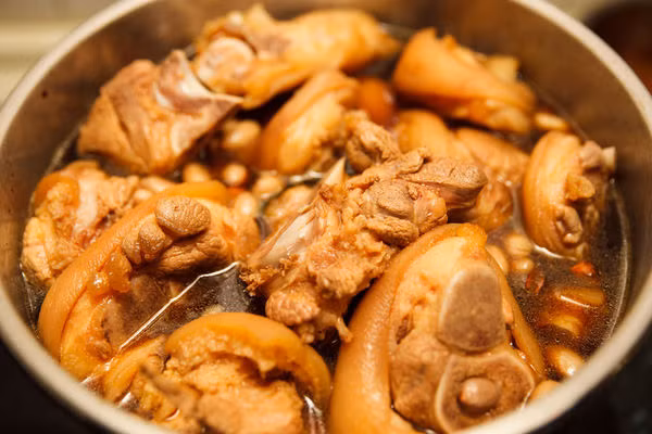 Đổ nước vào và đun sôi, sau đó cho nhỏ lửa và hầm trong khoảng 1 tiếng tới khi chân giò mềm bở. Nên sử dụng nồi áp suất để chân giò mềm nhanh hơn.