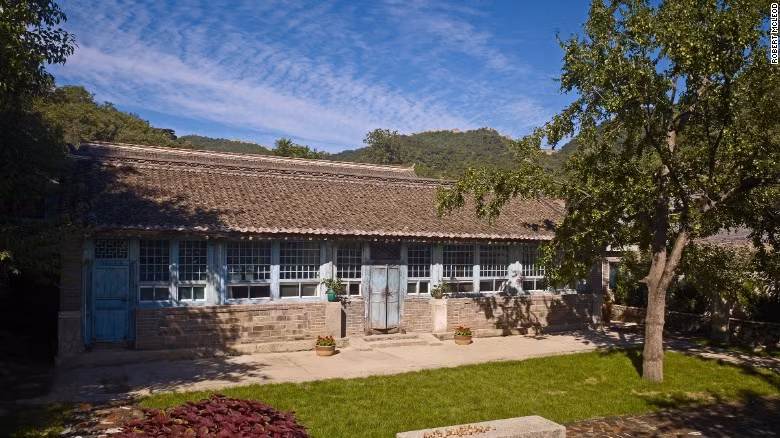 Trước đó, khi còn làm việc và sinh sống tại Bắc Kinh vào năm 1990, Spear và Liang quyết định cải tạo một ngôi nhà ở Mutianyu, cách thủ đô Bắc Kinh khoảng 80 km về phía bắc, thành một nơi nghỉ dưỡng vào cuối tuần. Bao quanh nhà là bầu không khí trong lành, con đường dài đi bộ và dễ dàng phóng tầm mắt ra Vạn Lý Trường Thành. Năm 2005 họ chuyển hẳn đến đây. Khi đó, cả làng chỉ có một trang trại trồng cây ăn quả là nguồn thu nhập duy nhất, người dân bỏ đi nơi khác làm ăn. Một năm sau, vợ chồng Spear bắt đầu đầu tư bất động sản vào làng Beigou ở gần đó.