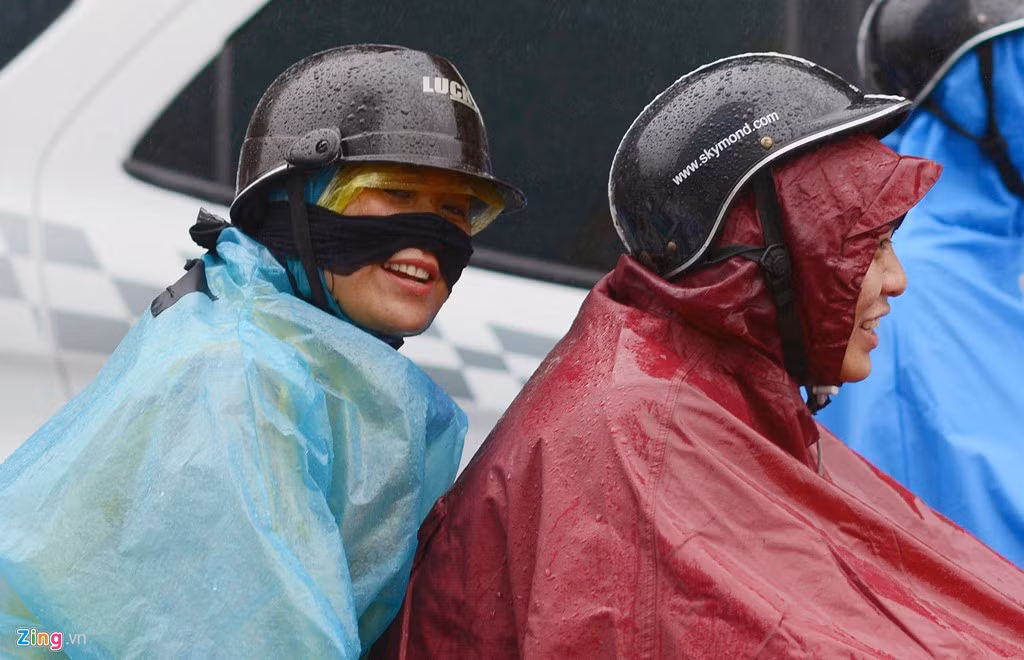 Hai người mắc kẹt giữa cơn mưa dù khá khổ sở nhưng vẫn cười đùa khi nhìn thấy ống kính máy ảnh. Ảnh: Tiến Tuấn.