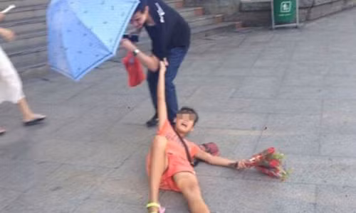 Cô gái túm tay lôi kéo, bắt ép người đi đường mua hoa.