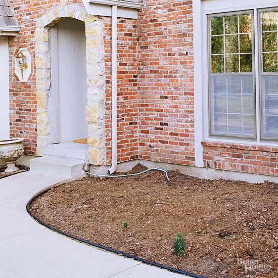 9. Phía trước nhà Trước khi cải tạo: Nền đất trống trơ trọi làm cho tường trát gạch trở nên thô ráp.