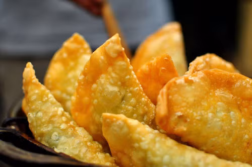 Bánh gối Bánh gối được xem là chiếc “bánh mùa lạnh” tại Hà Nội bởi khi này ăn không có cảm giác ngán, ngẩy như mùa nóng. Làm bánh gối khá kì công bởi cả vỏ và nhân bánh là sự tổng hòa của nhiều nguyên liệu. Trước hết là lớp bột mì bao ngoài làm vỏ bánh.Vỏ bánh vừa phải mềm dẻo để bao trọn nhân bánh, vừa phải đủ mỏng để khi rán lên có vị giòn ngậy đặc trưng. Nước chấm phải có một chút mặn, ngọt, một chút chua điểm xuyết vài miếng đu đủ, cà rốt làm dưa ghém. Tất cả hương vị tổng hòa tạo nên hương vị bánh rất đặc trưng, đủ để níu giữ nỗi mong mỏi của thực khách mỗi khi trời chuyển lạnh.