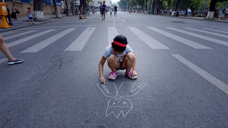 Bé gái thoải mái ngồi vẽ giữa lòng đường Đinh Tiên Hoàng.