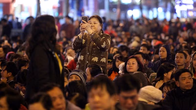 Chen chúc trong hàng vạn người bên ngoài chùa Phúc Khánh (Hà Nội) trong buổi lễ cầu an, nhiều người vẫn gắng chụp tấm ảnh lưu niệm.