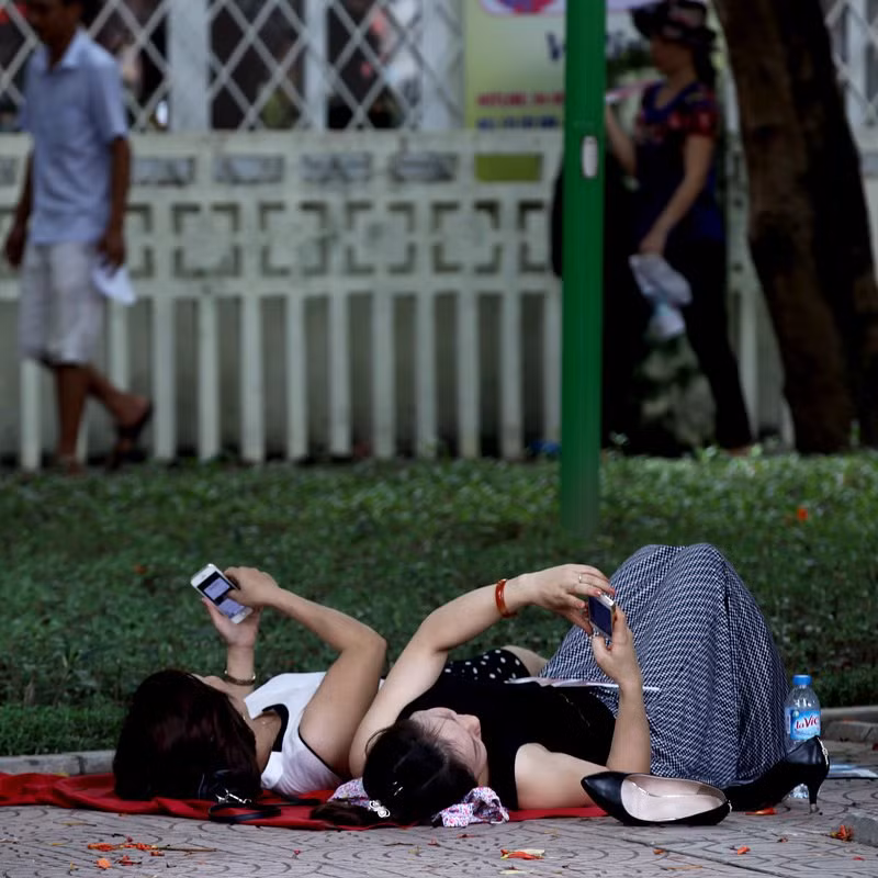 Phụ huynh giải khuây bằng smartphone trong khi chờ con cháu thi đại học tại điểm thi Đại Học Thủy Lợi - Hà Nội.