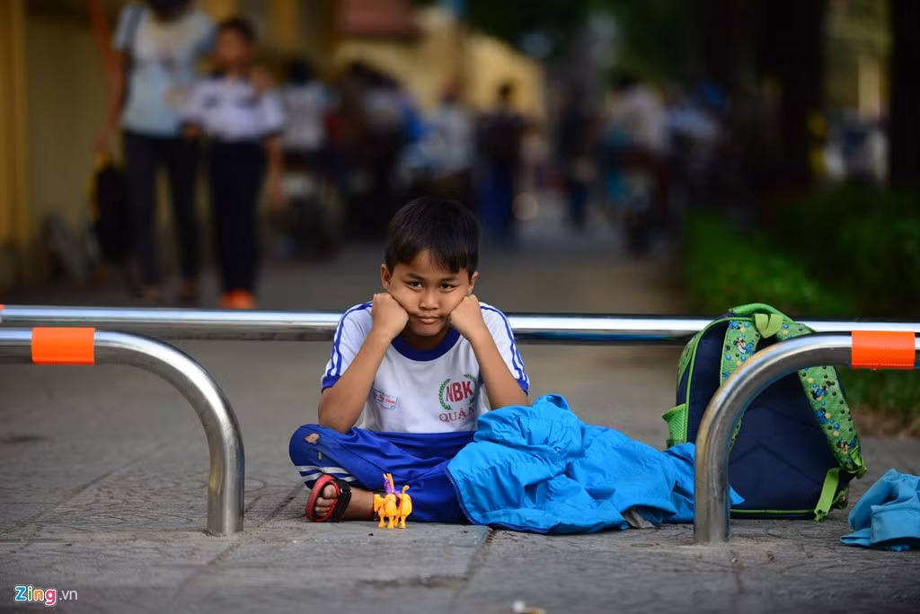 Em Quốc Huy, học sinh lớp 3 trường Tiểu học Nguyễn Bỉnh Khiêm ngồi chơi chờ cha đến đón về. Em cho biết hàng ngày vẫn ngồi đợi phụ huynh như vậy.