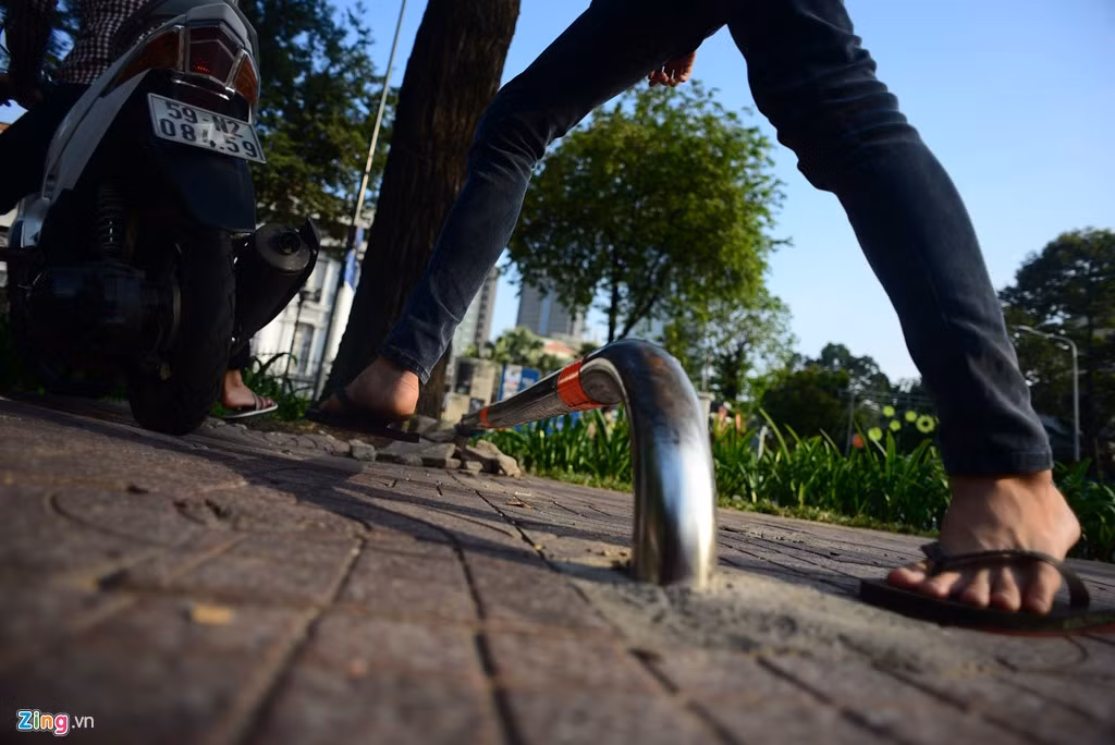 Một thanh niên ngồi sau xe xuống để người lái dễ di chuyển qua thanh chắn barie.