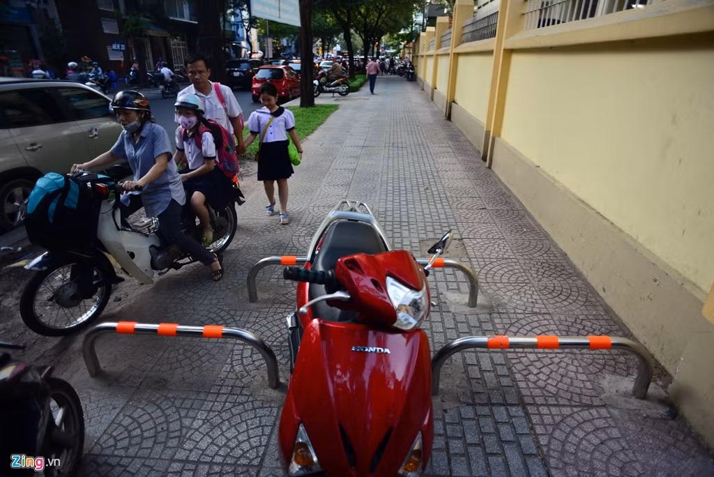 Một chiếc xe để ngay ở khoảng trống gắn thanh barie trên đường Nguyễn Bỉnh Khiêm, còn ngay gần đó phụ huynh đang leo vỉa hè chạy ngược chiều.