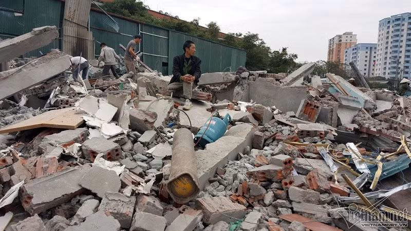 Một người đàn ông ngồi thẫn thờ trên đống đổ nát.