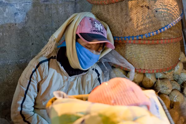 Không chỉ mặc áo ấm dày sụ, người phụ nữ đeo khẩu trang, quấn khăn kín mít để chống rét.