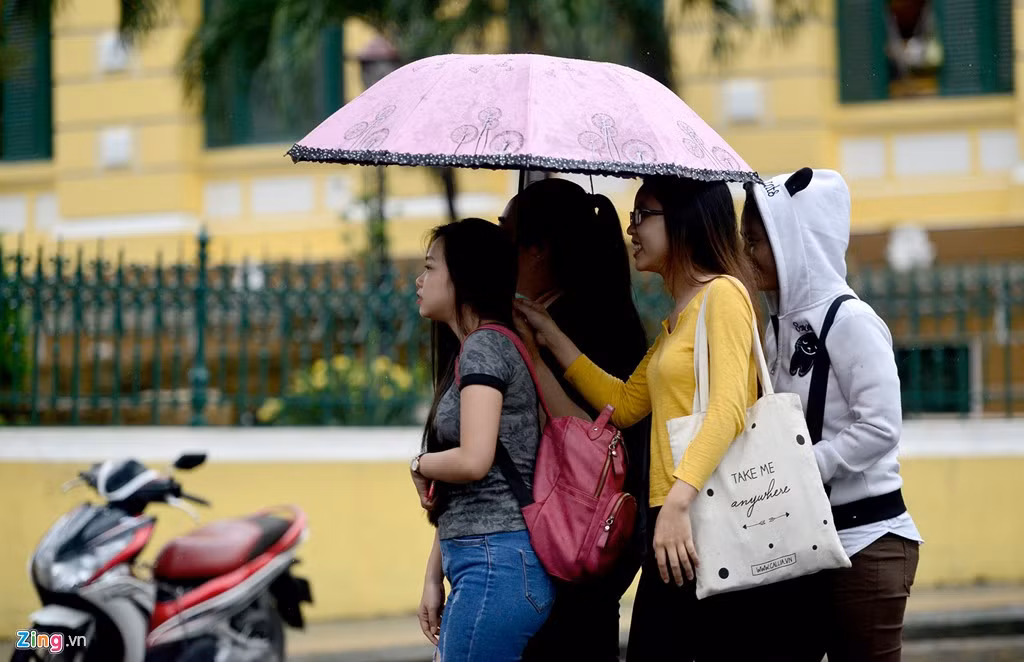 Bốn cô gái chung một chiếc ô dạo bộ trên Quảng trường Công xã Paris, quận 1.