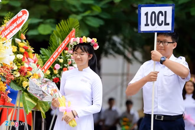 Một nữ sinh đội hoa trên đầu dẫn đầu lớp tiến về phía sân khấu.