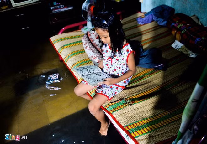 Cuộc sống đảo lộn ảnh hưởng tới học tập, sinh hoạt của cả người lớn lẫn trẻ nhỏ. Trong ảnh là bé Thạch Kiều My ngồi đọc truyện tranh trong nhà đầy nước.