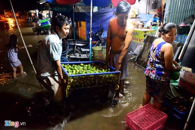 Các tiểu thương buôn bán ở cửa hàng mặt đường bị giảm doanh thu do vắng khách. Chủ một gian bán hoa quả phải chạy hàng tránh nước ngập.
