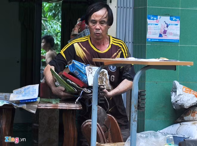 Người dân lấm lem bùn đất vất vả dọn dẹp đồ đạc.