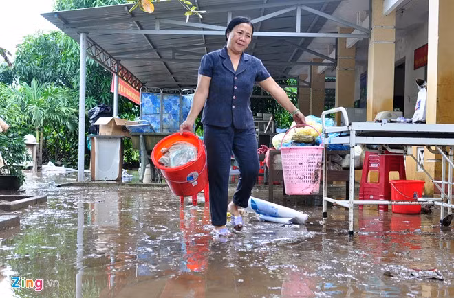 Bà Phạm Thị Luận, Phó trạm Y tế xã An Hiệp dọn dẹp bùn đất sau trận lũ quét. "Tôi đang trực ở cơ quan thì nghe nước chảy rào rào, tích tắc lũ dâng lên ngập đến nửa trạm. Thấy lũ lớn nhanh, tôi sợ quá liền mặc áo phao vào rồi cấp tốc điện thoại cầu lãnh đạo xã. Lực lượng cứu hộ đã dùng dây thừng buộc vào cơ thể rồi chia nhau kéo, dìu tôi thoát ra vùng ngập sâu nguy hiểm", bà Luận nói.