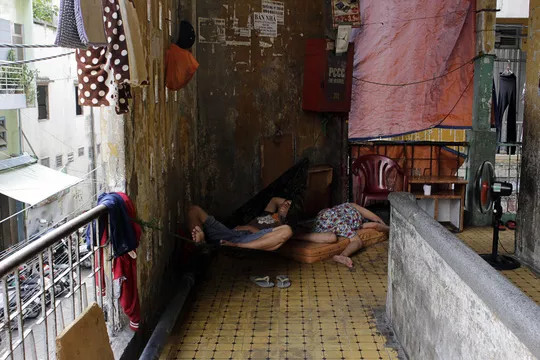 Hiện tại chung cư Cô Giang vẫn còn khoảng 300 hộ dân sinh sống. Trong ảnh: Người dân mang võng, chiếu ra hành lang ngủ để tránh cái nóng ban trưa.