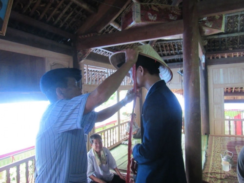 Ông nội đội nón cho cháu trai đi đón vợ.