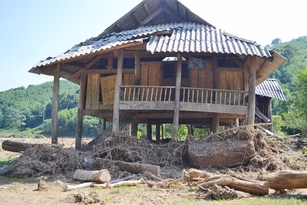 Ngôi nhà xiêu vẹo, phía dưới chất đầy gỗ, củi bị nước lũ kéo về.