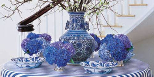 Tại hành lang. Nhà thiết kế Carolyne Roehm sử dụng một chiếc bàn tròn với khăn trải, hoa trang trí nhà có tông chủ đạo màu tím oải hương và trắng để làm nổi bật lên hành lang trắng lạnh lẽo. Nhược điểm gầm cầu thang tối và xấu cũng nhờ đó biến mất.