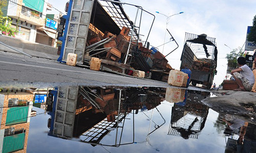 Xe tải lật nghiêng, hàng trăm lít dầu và mật ong tràn trên quốc lộ 1. Ảnh: Minh Hoàng.