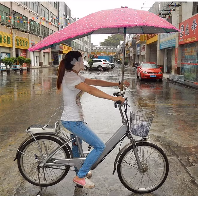 Còn đây là cách để một cô gái Trung Hoa đi xe đạp và né trời mưa. Một chiếc ô di động được gắn trên xe.