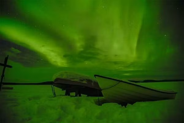 Những chiếc thuyền trên nền tuyết trắng dưới ánh sáng cực quang.